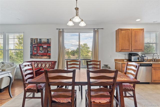 dining area with light wood-type flooring, a healthy amount of sunlight, sink, and an inviting chandelier