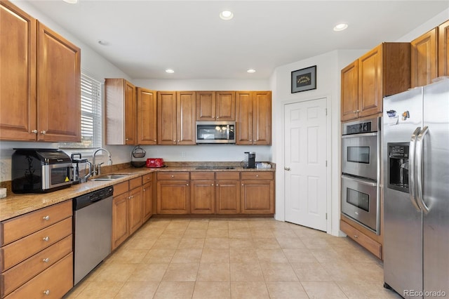 kitchen with light stone countertops, stainless steel appliances, sink, and light tile patterned floors