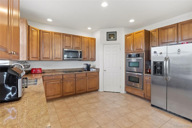 6470 S Ider St, Aurora, CO 80016 - kitchen with appliances with stainless steel finishes, brown cabinetry, light stone counters, recessed lighting, and light tile patterned floors