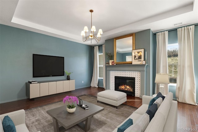 5693 Missoula Trl, Castle Rock, CO 80108 - living room featuring a chandelier, a raised ceiling, wood finished floors, and a tiled fireplace