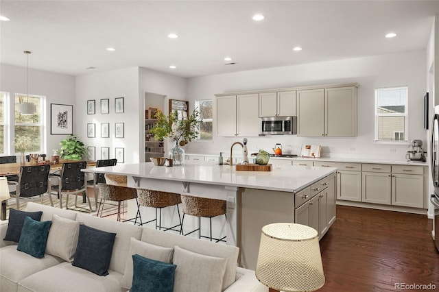 5693 Missoula Trl, Castle Rock, CO 80108 - kitchen with stainless steel microwave, light countertops, a kitchen breakfast bar, recessed lighting, and an island with sink