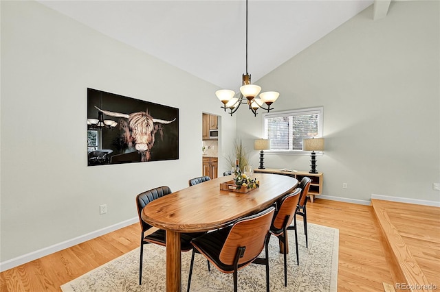 dining room with a chandelier, baseboards, light wood finished floors, and high vaulted ceiling