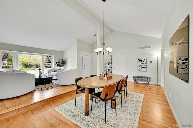 dining room with high vaulted ceiling, light wood finished floors, a chandelier, and baseboards