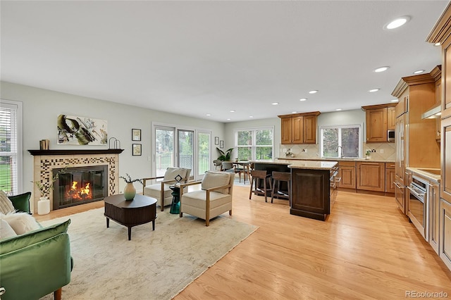 living room featuring light wood finished floors, a fireplace, and recessed lighting