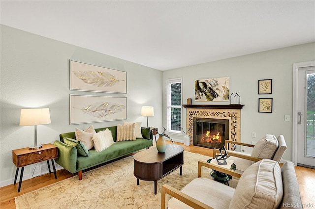 living area featuring wood finished floors, a tiled fireplace, and baseboards