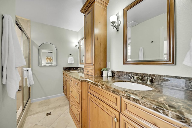 full bathroom with double vanity, a stall shower, baseboards, and tile patterned flooring