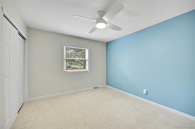 unfurnished bedroom with a closet, carpet flooring, baseboards, and a ceiling fan