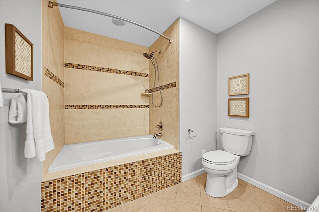 bathroom with toilet, tile patterned floors, tiled shower / bath combo, and baseboards