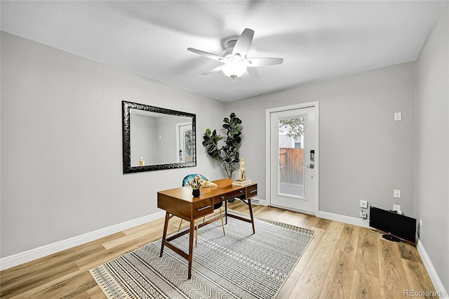 office area with baseboards, light wood-type flooring, and ceiling fan
