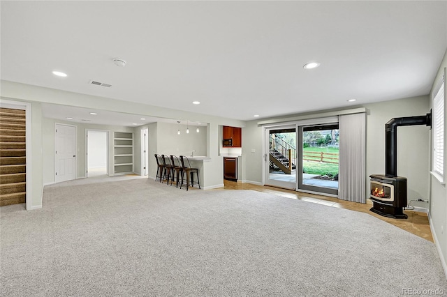 living area featuring stairs, baseboards, bar, recessed lighting, and light carpet
