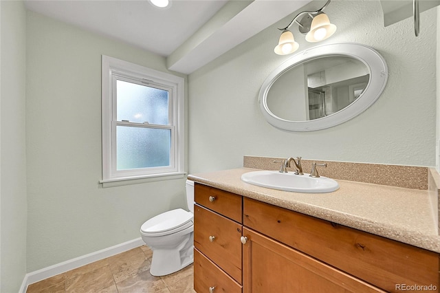 bathroom featuring toilet, baseboards, and vanity