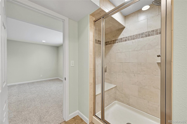 full bathroom with a shower stall and baseboards