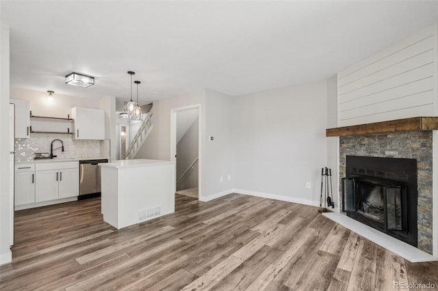 1707 Ostia Cir Unit 46, Lafayette, CO 80026 - kitchen with open shelves, dishwasher, white cabinetry, wood finished floors, and light countertops