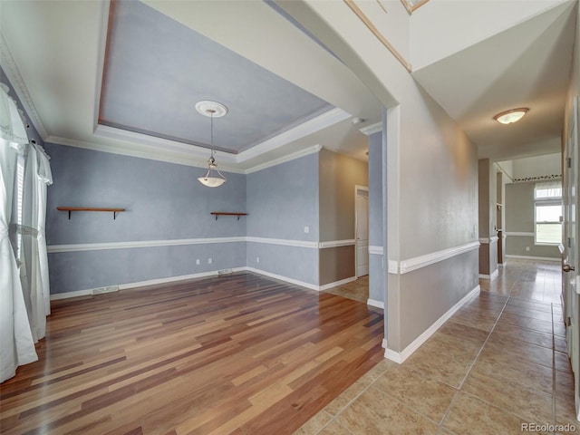 empty room with crown molding, a tray ceiling, and light hardwood / wood-style floors