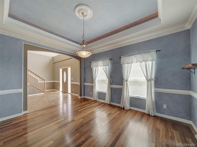 interior space with ornamental molding, a tray ceiling, and hardwood / wood-style floors