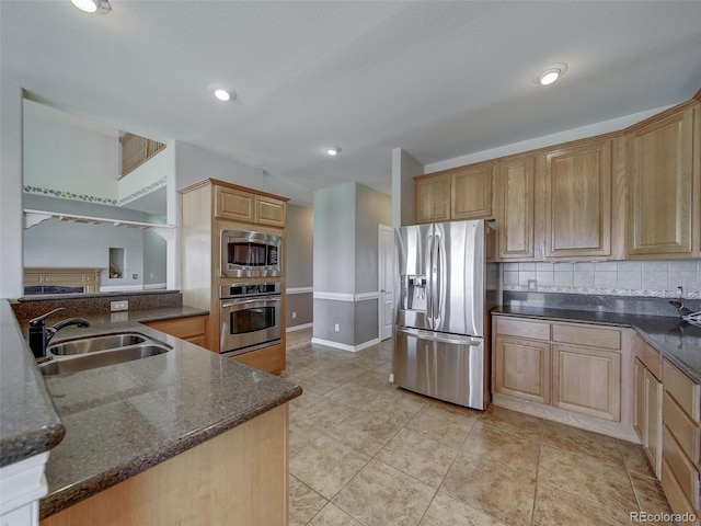 kitchen featuring sink, dark stone countertops, backsplash, stainless steel appliances, and light brown cabinets