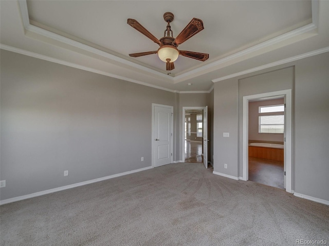 carpeted empty room featuring a raised ceiling, ornamental molding, and ceiling fan