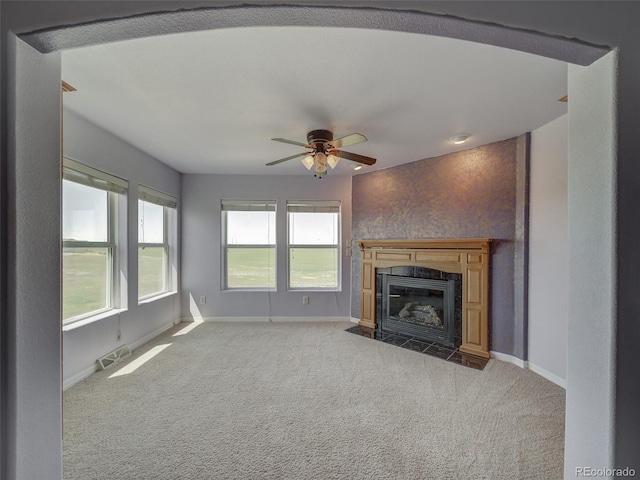 unfurnished living room with ceiling fan, carpet flooring, and a tiled fireplace