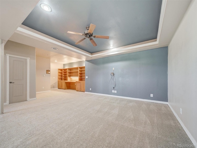 interior space featuring ceiling fan, a tray ceiling, and carpet floors