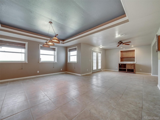 spare room with light tile patterned floors, a tray ceiling, a textured ceiling, and ceiling fan