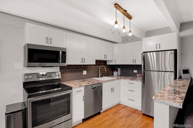 kitchen with decorative backsplash, white cabinets, stainless steel appliances, and a sink