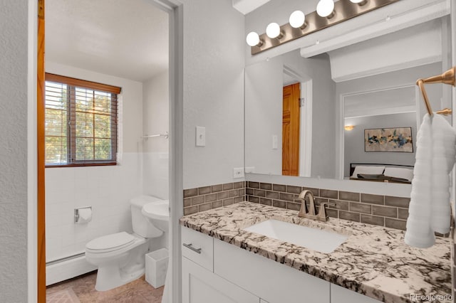 bathroom with a baseboard radiator, toilet, tile walls, and vanity