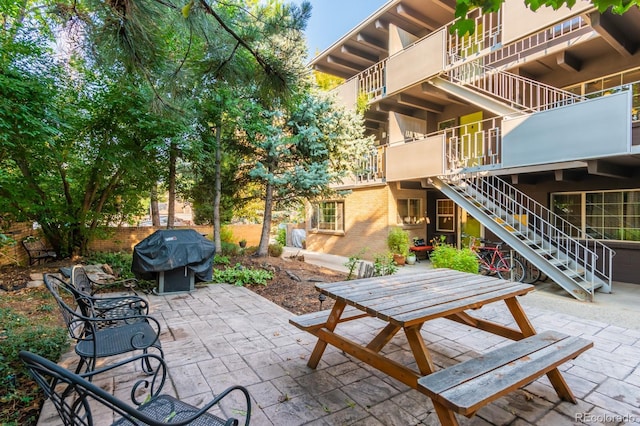 view of patio featuring stairs, outdoor dining space, and a grill