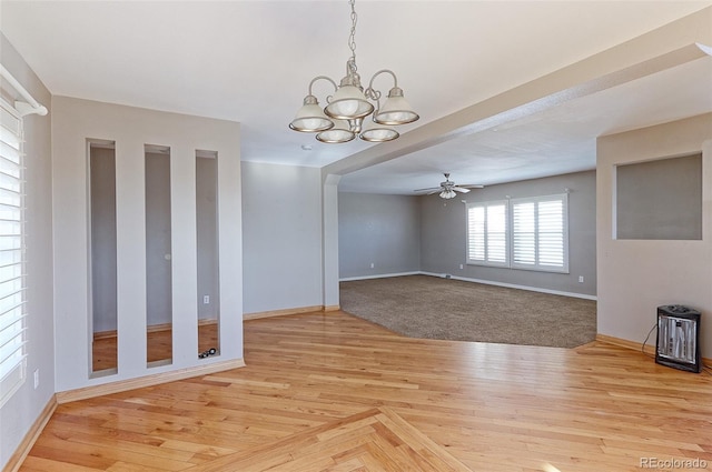 unfurnished dining area featuring ceiling fan with notable chandelier and light hardwood / wood-style flooring