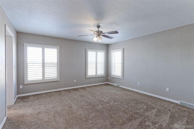 spare room featuring ceiling fan, a healthy amount of sunlight, carpet floors, and a textured ceiling