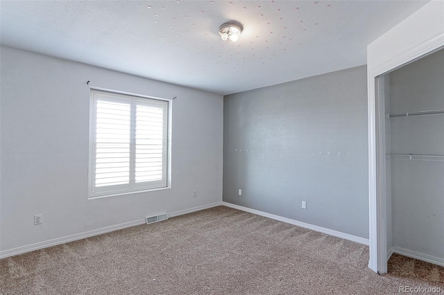 unfurnished bedroom with light colored carpet and a closet