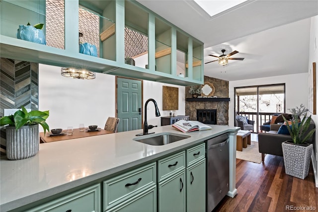 kitchen featuring dark wood-style flooring, a sink, a ceiling fan, green cabinets, and stainless steel dishwasher