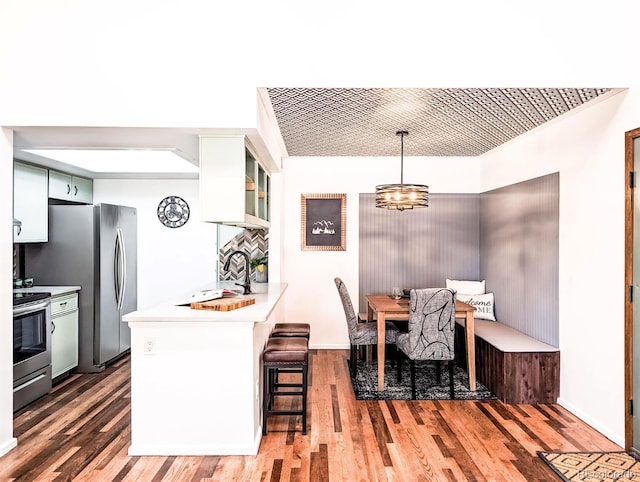 kitchen featuring a sink, light countertops, appliances with stainless steel finishes, a peninsula, and light wood-style floors