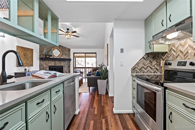 kitchen featuring tasteful backsplash, under cabinet range hood, appliances with stainless steel finishes, a sink, and green cabinetry