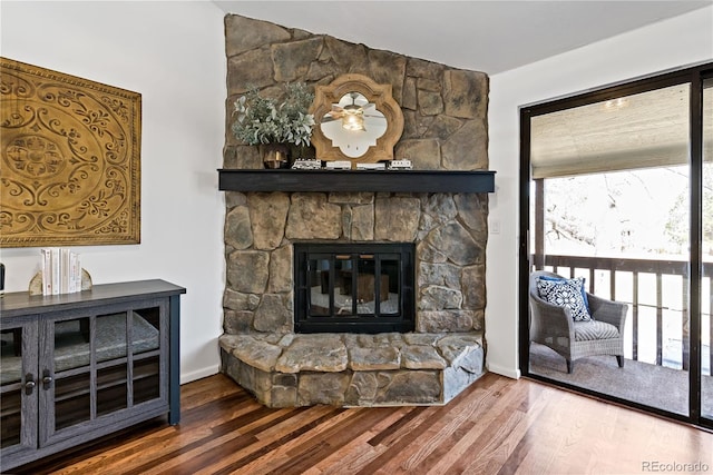 living area with a stone fireplace, wood finished floors, and baseboards