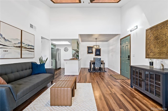living area featuring visible vents, a towering ceiling, and dark wood-style floors