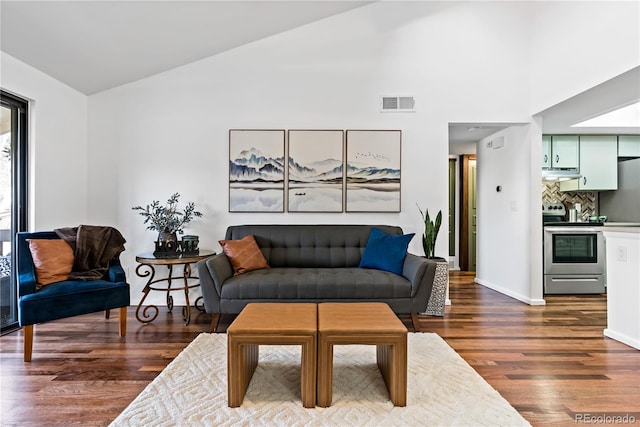 living room featuring dark wood-style flooring, visible vents, baseboards, and vaulted ceiling