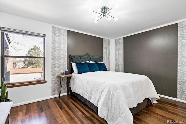 bedroom with baseboards, an inviting chandelier, and wood finished floors