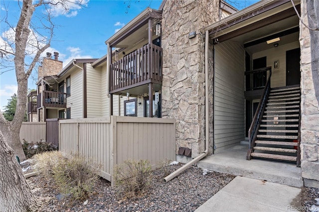 exterior space featuring stone siding, fence, and stairs