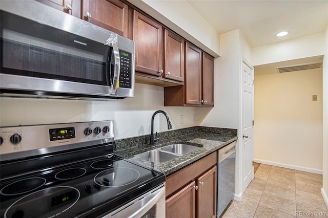 kitchen featuring light tile patterned floors, appliances with stainless steel finishes, sink, and dark stone counters