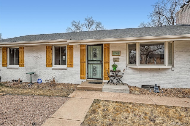 property entrance with brick siding, crawl space, and a shingled roof