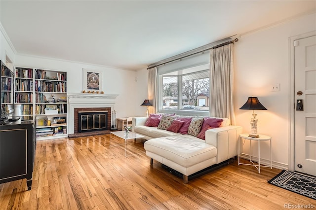 living room featuring light wood-style floors, a brick fireplace, and crown molding