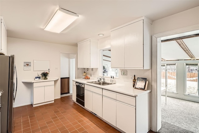 kitchen with black dishwasher, freestanding refrigerator, light countertops, white cabinetry, and a sink