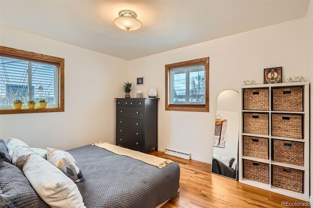 bedroom with light wood-style floors, a baseboard radiator, multiple windows, and baseboards