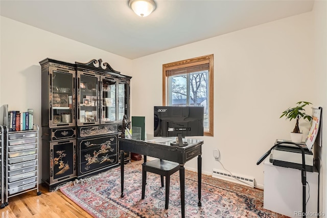 office space featuring a baseboard heating unit, light wood-style floors, and baseboards