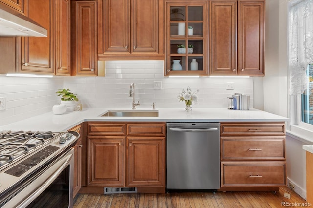 kitchen with tasteful backsplash, appliances with stainless steel finishes, sink, and light wood-type flooring