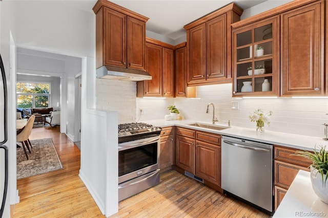 kitchen with sink, backsplash, stainless steel appliances, and light hardwood / wood-style flooring