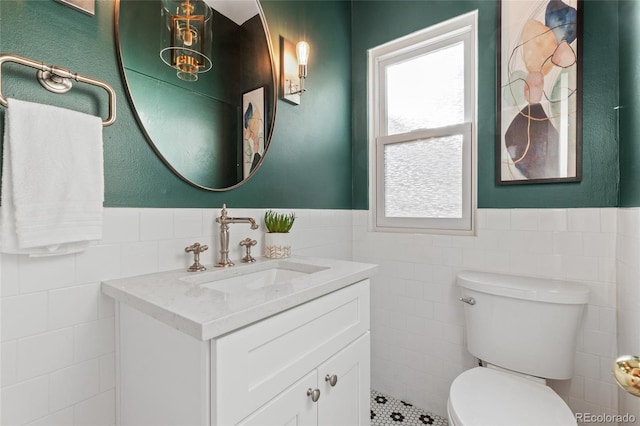 bathroom with vanity, toilet, and tile walls