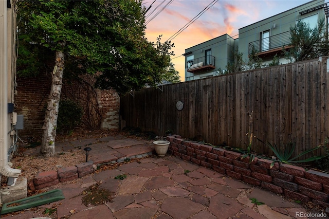 patio terrace at dusk featuring a balcony