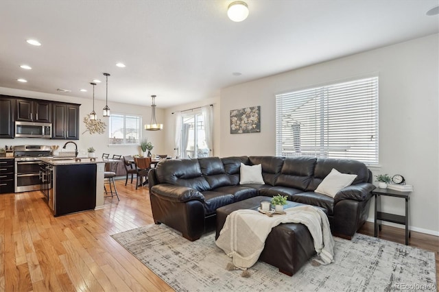 living room featuring sink, a wealth of natural light, and light wood-type flooring