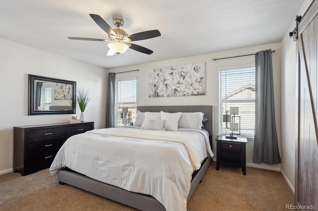 bedroom with ceiling fan, light carpet, and a barn door